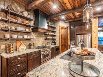 The kitchen houses stainless steel appliances and floating shelves.