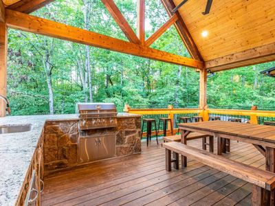 Built-in outdoor kitchen complete with a sink, grill, and trash facilities