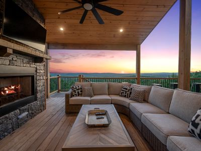 The covered patio has an oversized sectional around a stone gas fireplace.