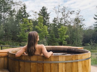 Hot tub centrally located between the pool house and the main house with views of the forest.