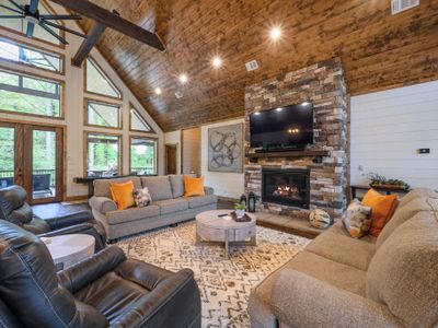 Luxury seating is placed around the stone fireplace and tv.