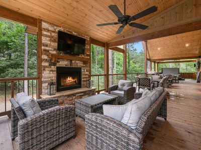 Covered patio has outdoor seating around the fireplace and tv!
