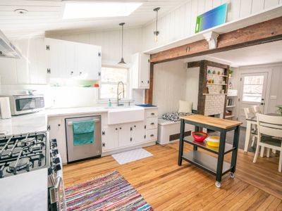 Modern eat-in kitchen with gas stove, farm kitchen, marble countertops and dishwasher.