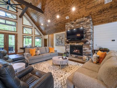 Luxury seating is placed around the stone fireplace and tv.
