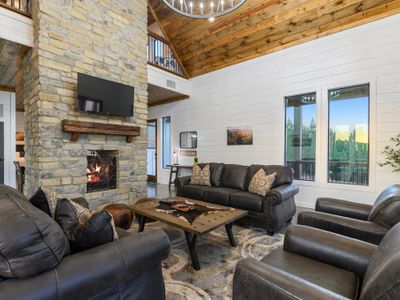 Leather couches and lounge chairs sit around the fireplace and tv!