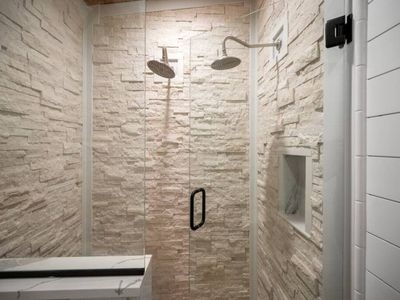 Multiple shower heads in the stone walk-in shower.