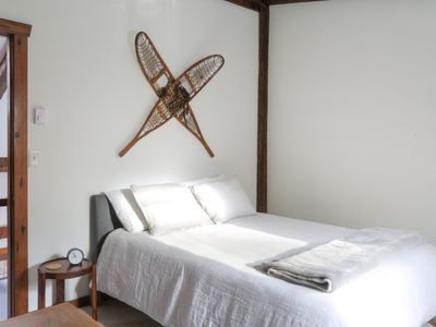 The snowshoe bedroom has a queen bed with luxury linen bedding and features art representative of winter recreation in the Catskills.