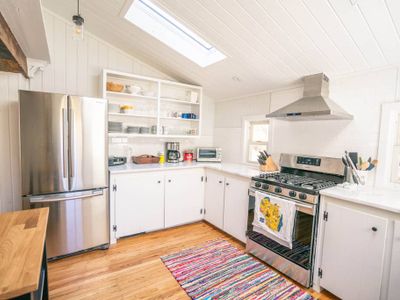 Modern eat-in kitchen with gas stove, farm kitchen, marble countertops and dishwasher.