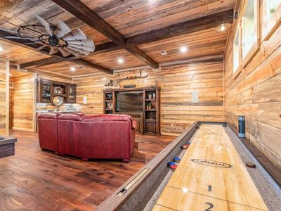 A shuffle board table as well as a flat screen TV in the game room.