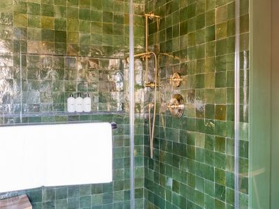 Vibrant tile accentuates a magnificent shower with brass fixtures.