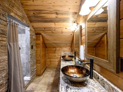 Shared bathroom with bunk room has double vanity and walk-in shower.