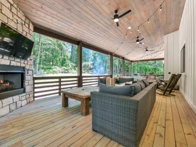 An oversized outdoor sectional is placed around the fireplace and tv.