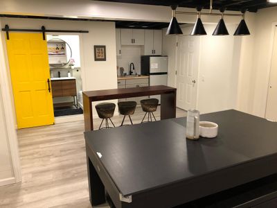 Open concept downstairs with mini kitchen, bathroom, and pool/ping pong table.