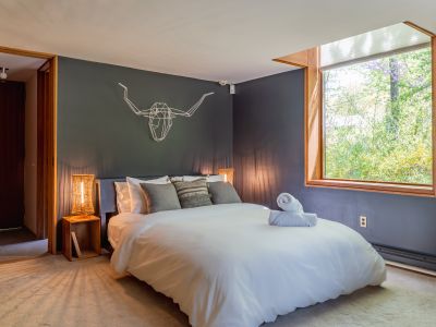 An immense picture window fills this moody and chic bedroom with light.