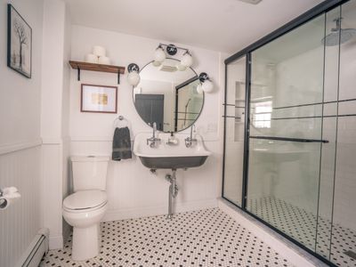 The primary bedroom's ensuite bath is updated with new accents like the rain shower, while tastefully honoring  early American design.