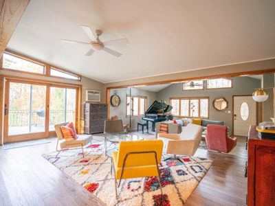 Open concept living room area with sectional, smart TV and grand piano.