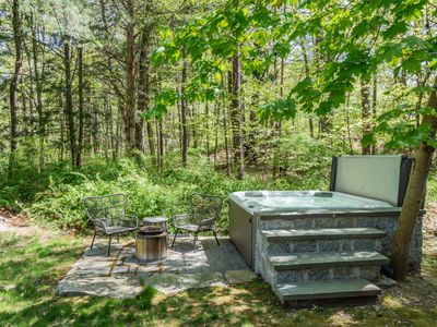 The hot tub and fire pit are perfect for cool nights, surrounded by greenery.