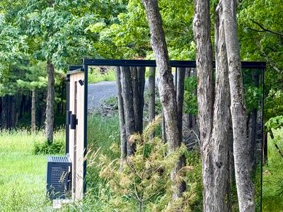 Nestled among the trees, the mirrored retreat reflects the summer woods on every side.