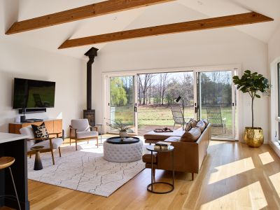 The living room in the main house features a functional wood stove, and sliding glass doors that open onto the hot tub deck.