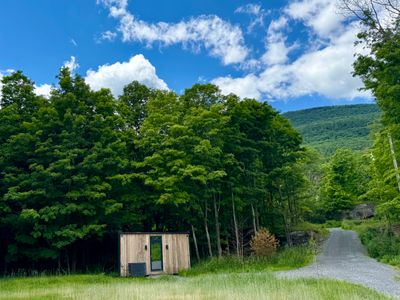 The guest house at the meadow's edge, a gravel drive winding toward the Catskills.