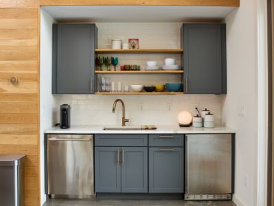 The pool house kitchenette features a dishwasher and mini fridge with ice maker, perfect for easy outdoor entertaining.
