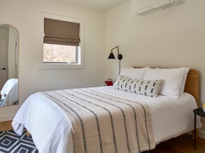 Across from the primary bedroom in the main house sits the first guest bedroom, looking out onto the pool and private meadow.