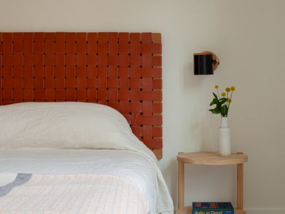 Restful primary bedroom with a woven leather headboard and curated design books.