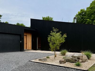 Arrive to a striking black-wood facade, a warm wood entry, and sculptural stone gardens.