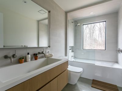 A clean, spa-like bath with a floating oak vanity, deep soaking tub, and a window framing the outdoors