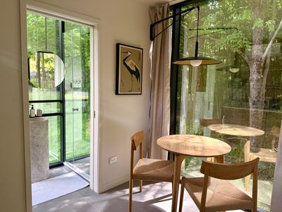 The dining nook opens through to the glass-walled water closet and forest beyond.