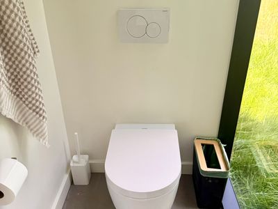 A sleek, modern water closet with a peaceful green outlook.