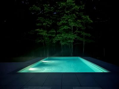 Slip into the glowing pool after dark, framed by softly lit trees.