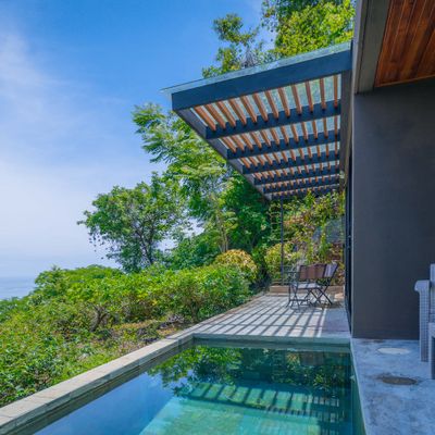 Unwind beside the private pool, surrounded by lush greenery and coastal views.