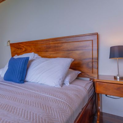 A comfortable bedroom setup with soft linens, bedside lighting, and elegant wood accents.