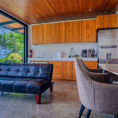 A cozy open-plan living area with kitchen access and warm tropical design details.