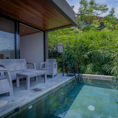 Covered poolside sitting area with peaceful greenery all around.