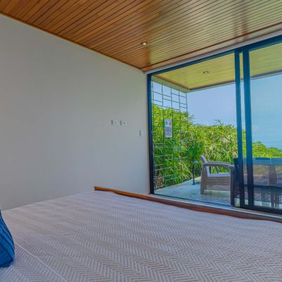 Bedroom with large sliding doors opening to lush greenery and natural light.