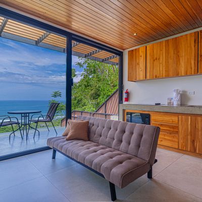 A bright and inviting living space with kitchenette, comfortable seating, and ocean views.