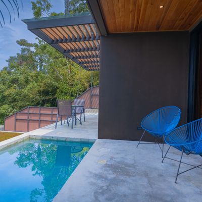Covered poolside terrace with lounge seating and beautiful coastal views.