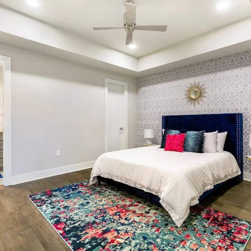 Serene queen bedroom w/ crisp white bedding & a pop of color from accent pillows.