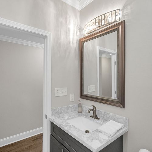 Newly constructed second bathroom w/ warm wood-framed mirror & modern fixtures.