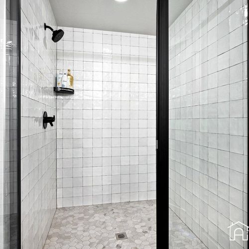 - step into this beautifully tiled walk in shower with striking black hardware throughout
- textured white tile and stone floors add spa style detail and modern appeal
- glass door enclosure keeps the space bright and spacious for daily comfort