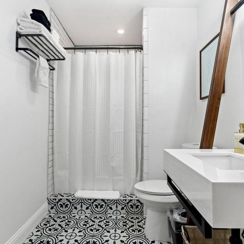 Clean, white bathroom w/ a tub & shower curtain — simple & fresh.