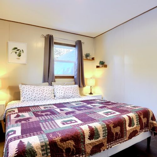 - sleep peacefully in a king bed adorned with a woodland themed quilt & plush pillows
- soft lighting from twin lamps & rustic wood shelves make this space warm & inviting
- wake up to views of nature & calming decor that feels like home in the woods