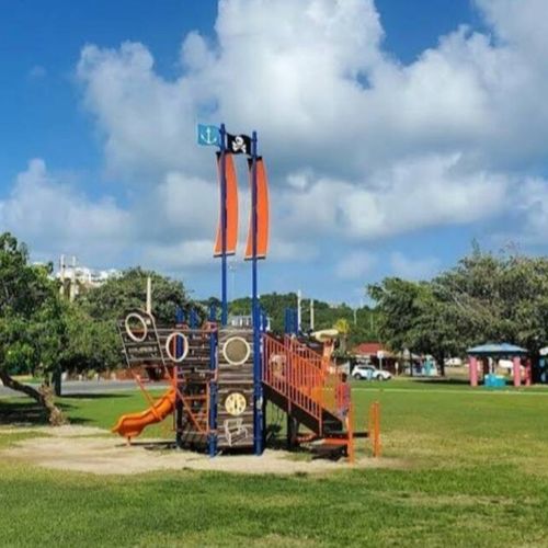 Family fun meets iconic landmarks! Enjoy this vibrant pirate-themed playground with the striking Puerto Rico flag monument in view.
