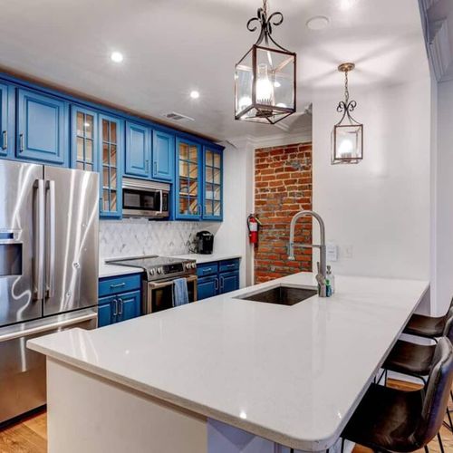 Sleek kitchen w/ stainless steel appliances & bold blue cabinetry.