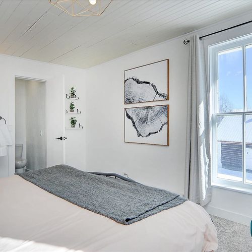 - airy bedroom with spa like ensuite, pedestal sink, and minimalist decor
- large windows bring in natural light and showcase beautiful seasonal views
- layered textures, soft linens, and thoughtful accents create a relaxing escape