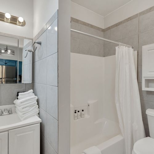 Spotless bathroom w/ fresh towels stacked & ready — clean & hotel-crisp.