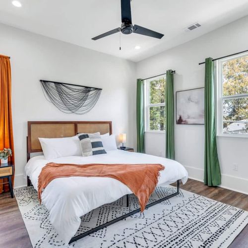 Upstairs king bedroom bathed in natural light w/ vibrant orange accent wall.