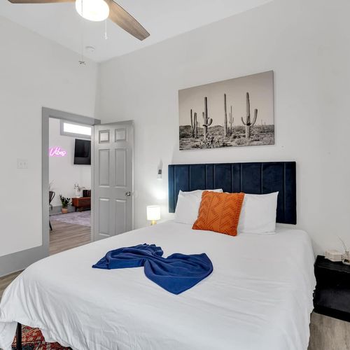Cozy bedroom w/ plush bed, navy throw, & warm earthy tones for a restful retreat.